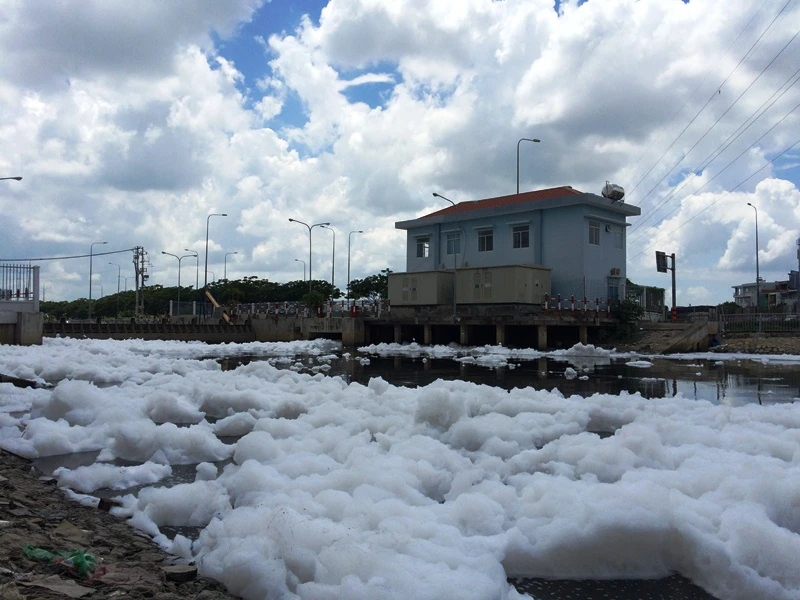Bọt trắng nổi xếp thành lớp khá dày xuất phát từ một trạm bơm điều tiết nước. 